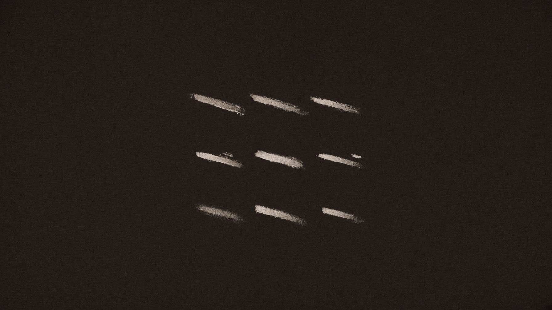 Nine pale marks in three groups on a dark field. The repetition is visible.